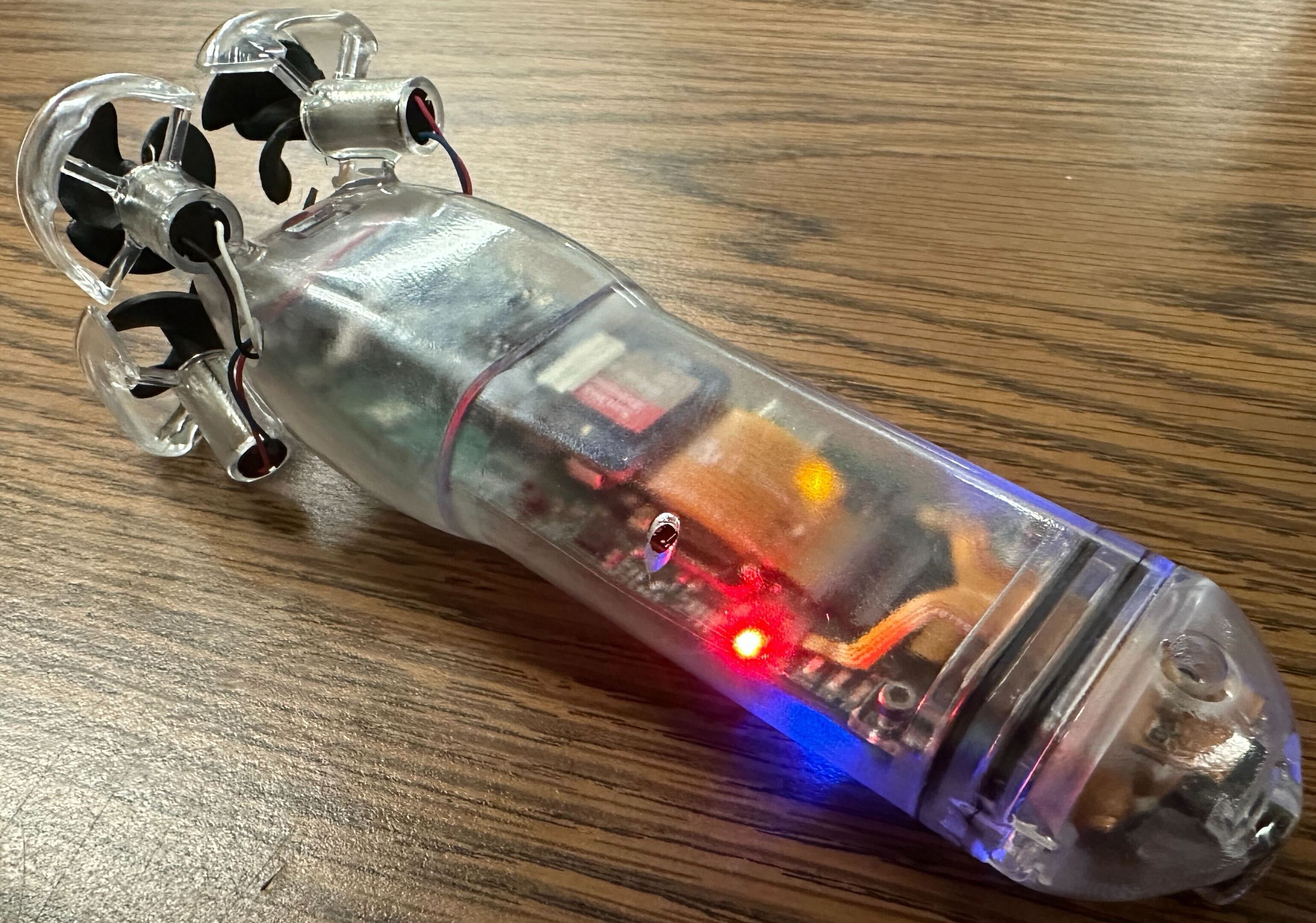 The autonomous torpedo powered on, with its internal electronics and status lights visible through the transparent hull