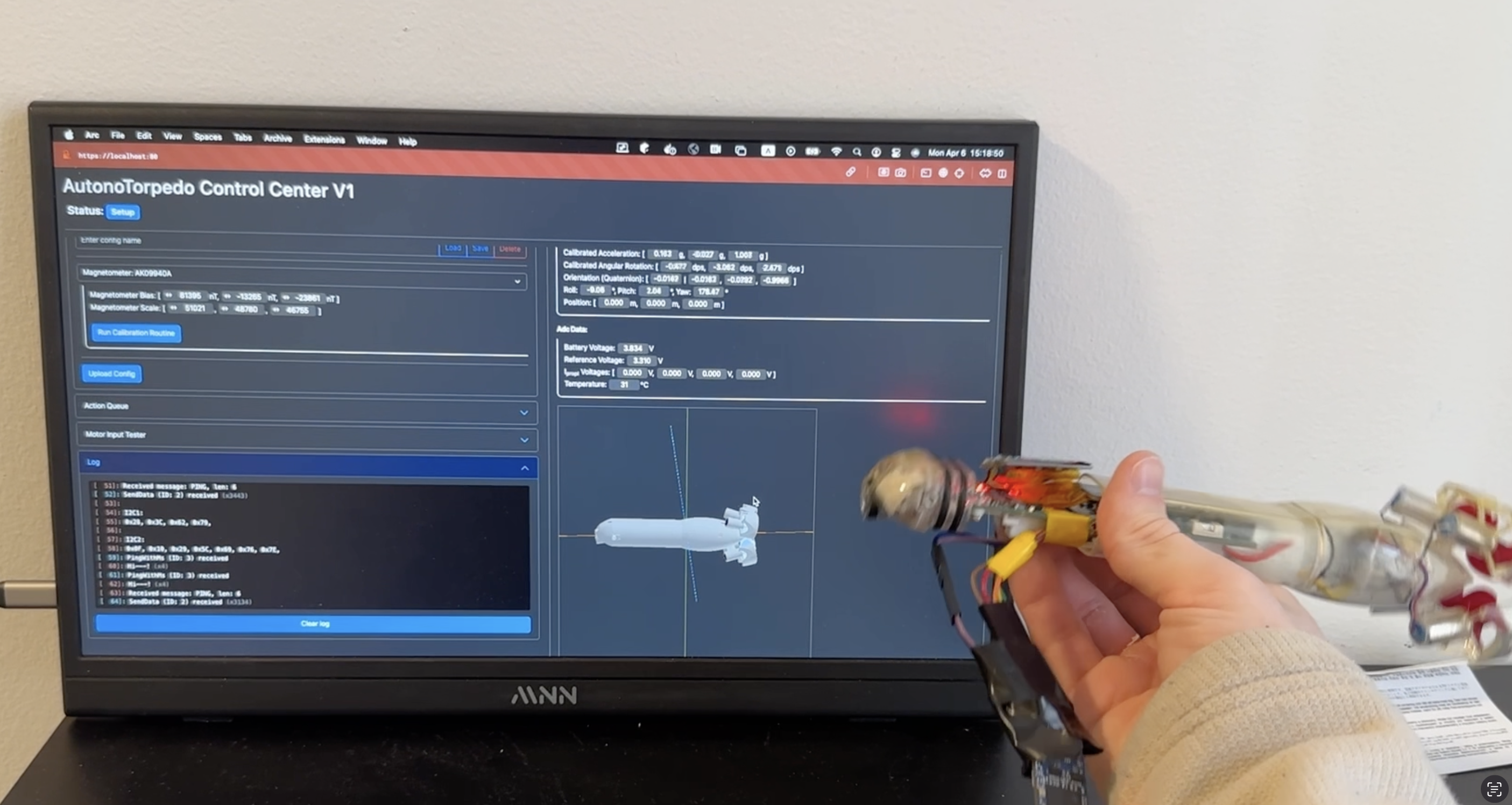 A monitor showing the AutonoTorpedo Control Center interface with live sensor readouts while the torpedo is held in front of it