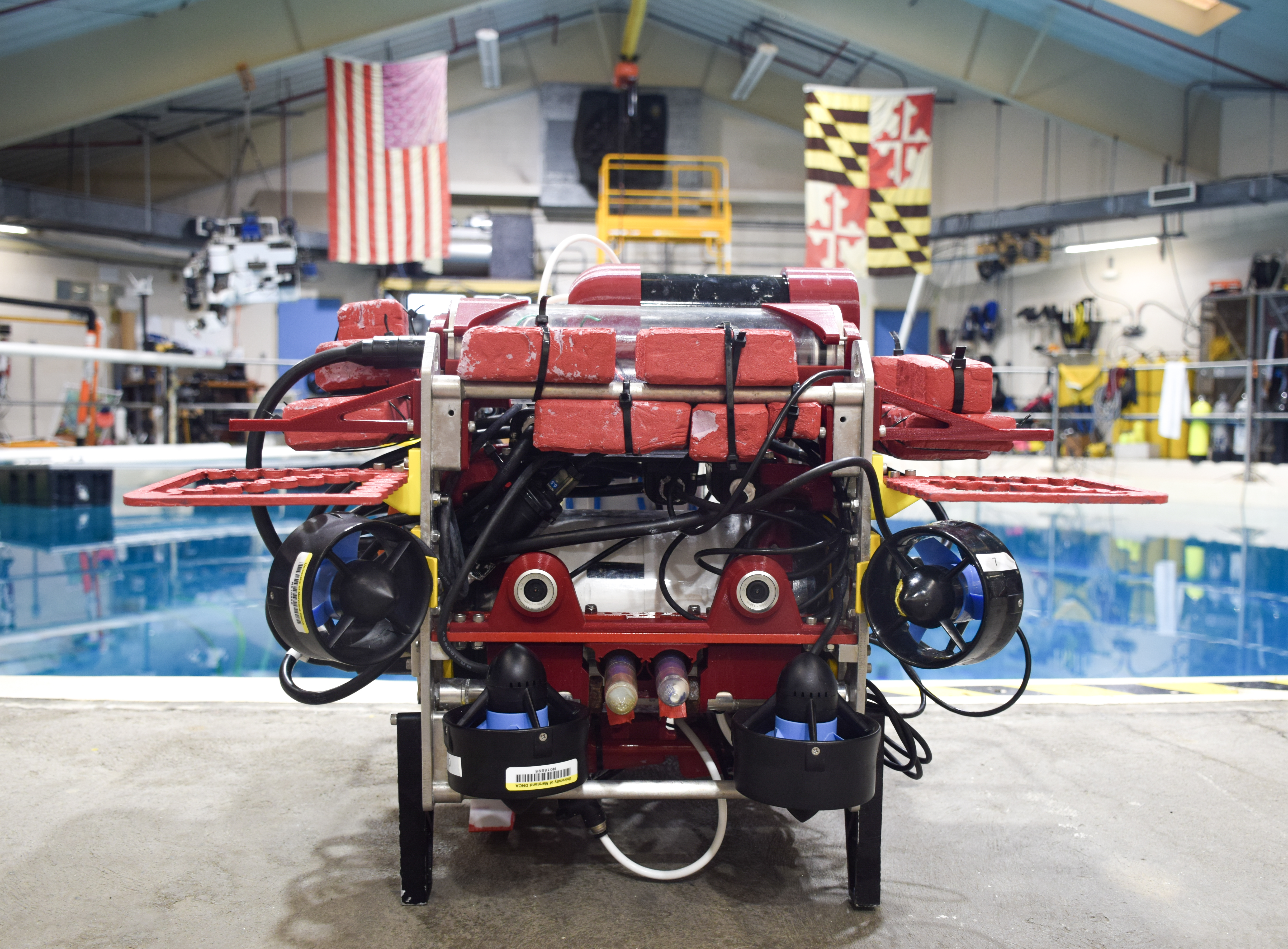 Qubo, a red-framed autonomous underwater vehicle, on the pool deck